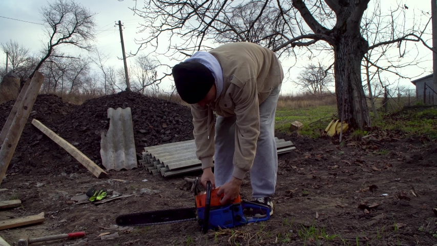 A man starts a chainsaw, preparing for construction work