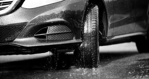 Reflecting everything around with its glossy surface, the premium car rides in extreme conditions - on a puddle on the road, where a large stream of spray erupts from under the wheels