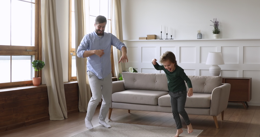 Playful crazy young daddy and cute kid son having fun dancing together in living room interior, happy funny active child boy copy father jumping laughing at home, carefree male family leisure indoors Royalty-Free Stock Footage #1041538618