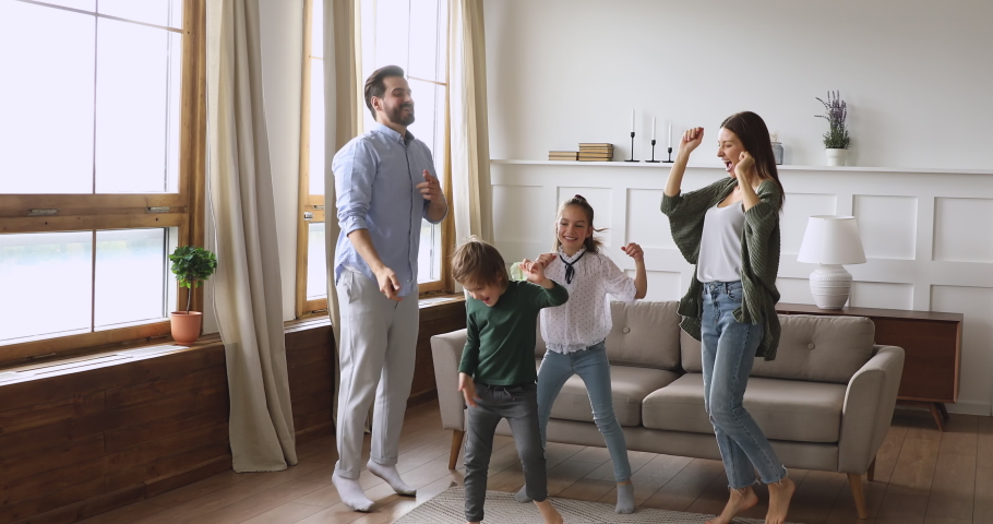 Crazy happy family young adult parents mum dad and cute funny active little children kids listening music dancing jumping together having fun in modern living room enjoying leisure lifestyle at home Royalty-Free Stock Footage #1041538723