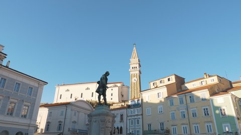 4k video. Camera moving shot. Central square with a monument and an ancient watch tower in Piran, Slovenia.