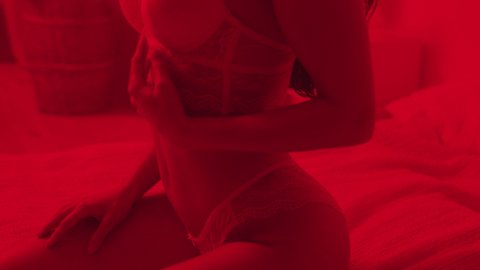 Portrait of sexy woman sitting in lingerie at red light room. Closeup provocative woman posing in erotic underwear in slow motion. Sensual woman body. Naked woman in lace lingerie.
