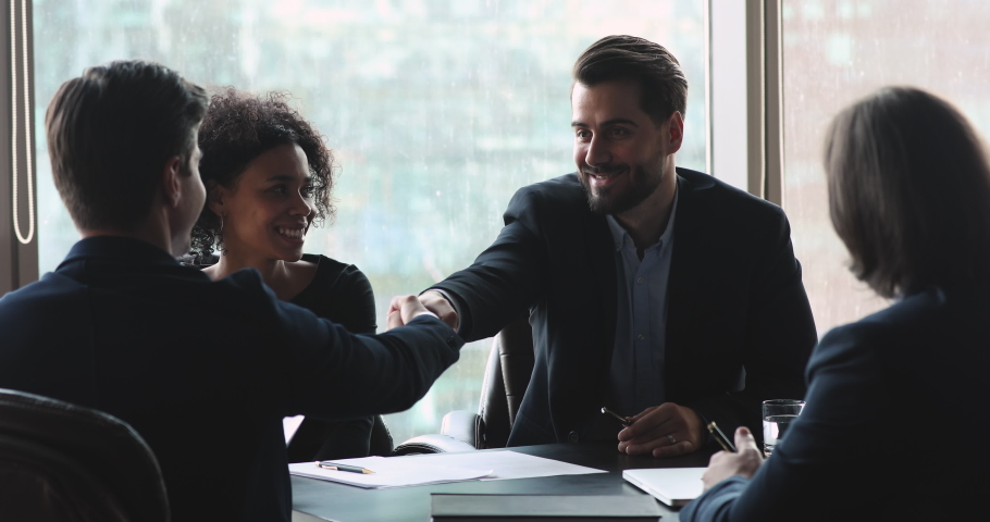 Smiling male executive wear suit make business agreement handshake businessman partner express respect and gratitude after successful team negotiations at international corporate group meeting