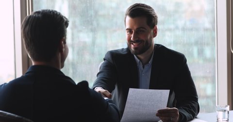 Confident businessman make agreement handshake business partner at meeting, male manager offering partnership contract to client customer, employer shake hand hire candidate at job interview concept