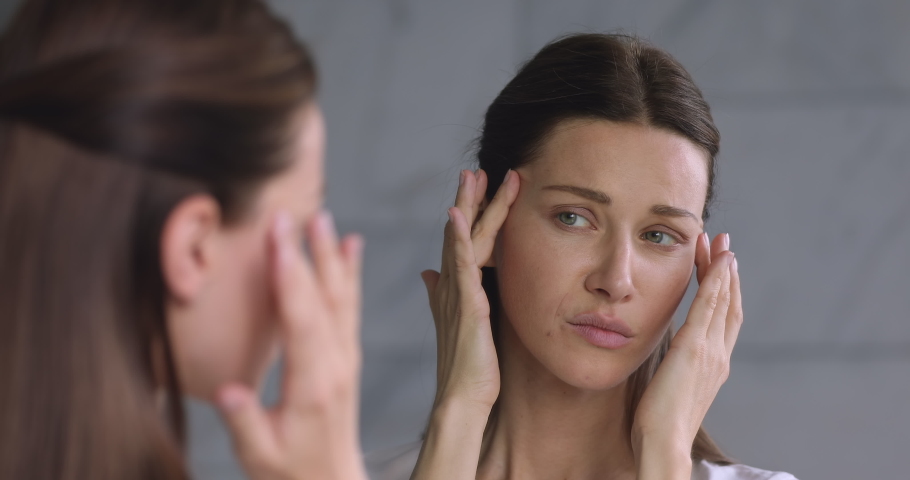 Worried young adult 30s woman looking in mirror feeling stressed about facial wrinkles problem, frustrated upset lady touching face depressed about dry sensitive aging skin care concept in bathroom Royalty-Free Stock Footage #1041547765