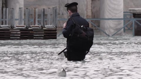VENICE, ITALY - November 12, 2019: Policeman walking on the flooded streets  (acqua alta) in Venice, Italy. Venice high water. 4k