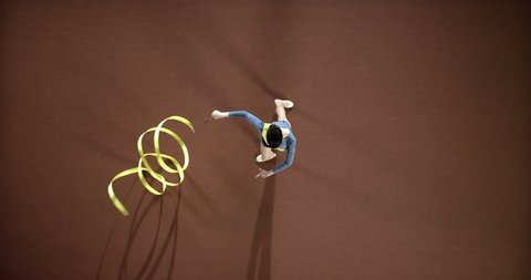 Girl gymnast performs exercises with a yellow ribbon. Top view. Slow mo, slo mo, slow motion, high speed camera