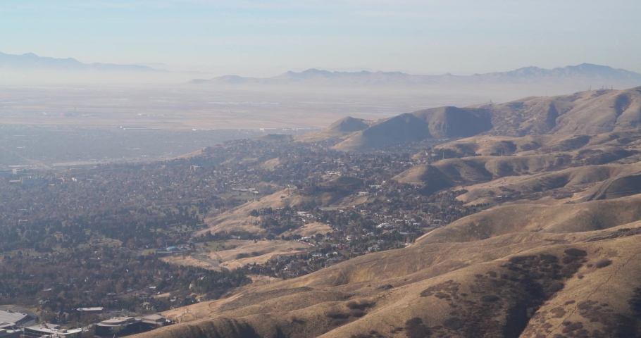 Pan to the left of a telephoto view of downtown Salt Lake City with a bird flying through the center frame