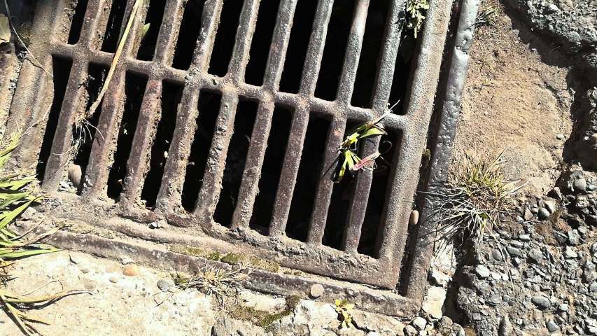 Rusty metal grill in broken asphalt from above