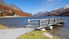 Wonderful morning view of Sils lake. Orange larch trees on the hills in Swiss Alps. First snow covered high mountain ranges. Autumn landscape os Switzerland, Europe. Full HD video (High Definition).