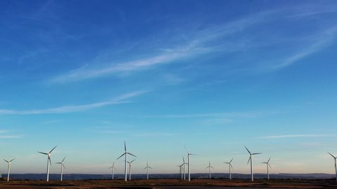 Windmills for electric power production in rural environment with wind farm for spinning renewable energy, metal turbines doing electricity against beautiful blue sky
