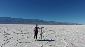 Professional photographer standing near tripod with equipment for shooting video of landscape and scenic views in death valley, skilled hipster girl making picture on camera in wild desert