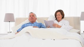 Retired Caucasian couple reading in the bed 