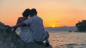 Young couple sit on the rock and wait for sunset. RAW video record.