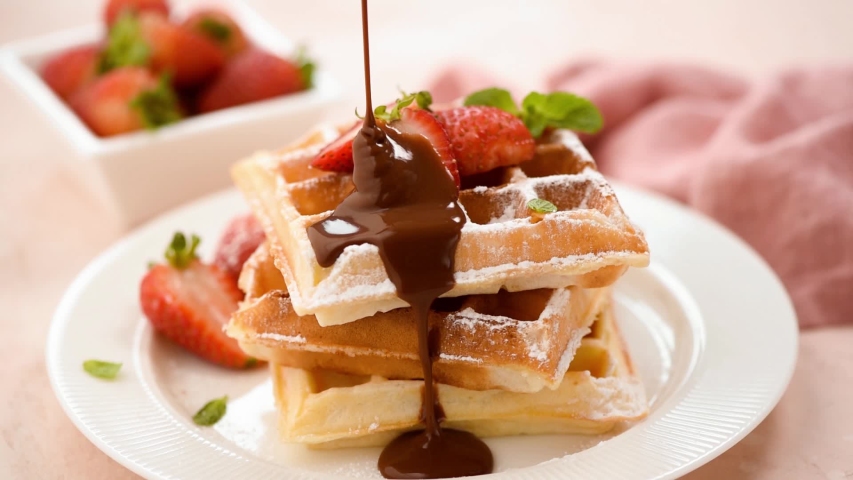 Chocolate sauce pouring on belgian waffles. Sweet breakfast food, unhealthy eating. Sugar food | Shutterstock HD Video #1041579232