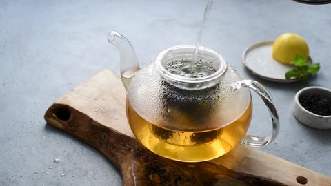 Process of Brewing tea with lemon and mint in transparent glass tea pot