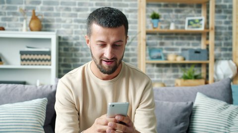 Carefree middle-aged guy is chatting online texting having fun at home alone enjoying communication. Modern devices, happiness and lifestyle concept.