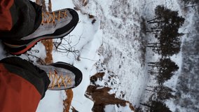 Vertical POV video of a hiker's legs sitting on top of a mountain.