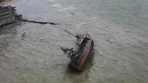 Odessa, Ukraine - 24 of November 2019. Aerial drone flight view of tanker Delphih wreck Ship rolled over lie on side sand beach dolphin Spill fuel float poisoning polluting water Tecnological disaster