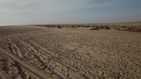 4K aerial drone video view of Namibian Atlantic coastline, sand beach with human footprints and car wheels tracks in Skeleton Coast Park landscape with ocean background at Namibia's west coast
