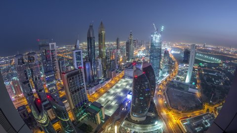 Skyline of the buildings near Sheikh Zayed Road and DIFC aerial night to day transition timelapse in Dubai, UAE. Modern towers and illuminated skyscrapers in financial center and downtown before