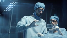 Professional Surgeon and Assistant Analyze Patient Diagnosis Data on Transparent Phones During Surgery. Modern Hospital Operating Room. Shot on RED Epic-W Helium Camera. - Powered by Shutterstock - Get 15% off with code: PIKWIZARD15