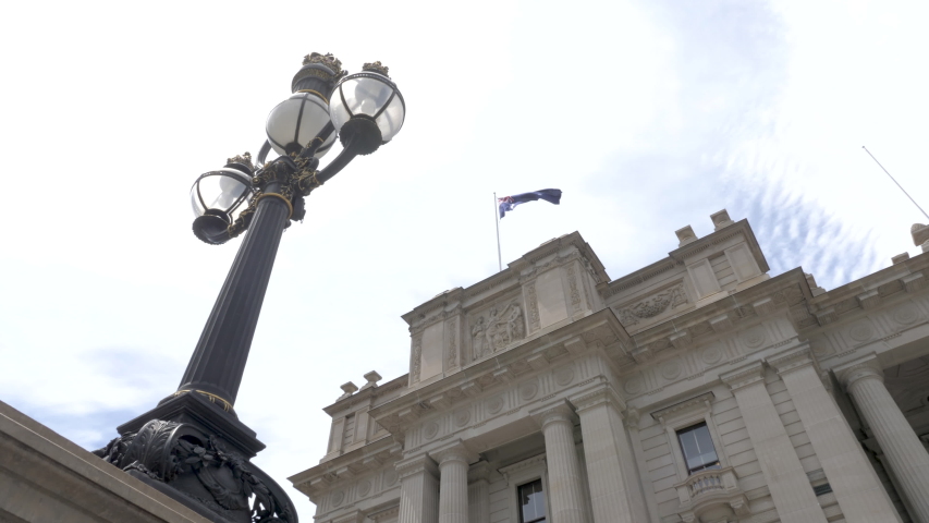 Detail of parliament of Victoria architecture in Melbourne. Australian flag waving, slow motion. 