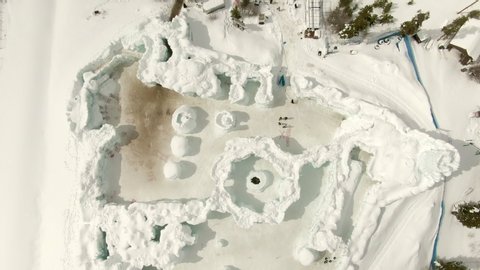 Aerial: Drone descending over tourists standing at Ice Castles during winter on sunny day - Silverthorne, Colorado