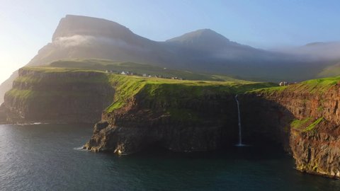 4k drone forward video (Ultra High Definition). Majestic morning scene of Mulafossur Waterfall. Stunning summer view of Vagar island, Faroe Islands, Denmark. Beauty of nature concept background.