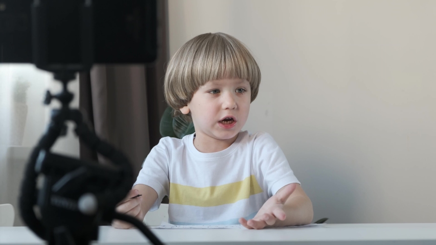 Little cute blogger shooting video for social media with smartphone