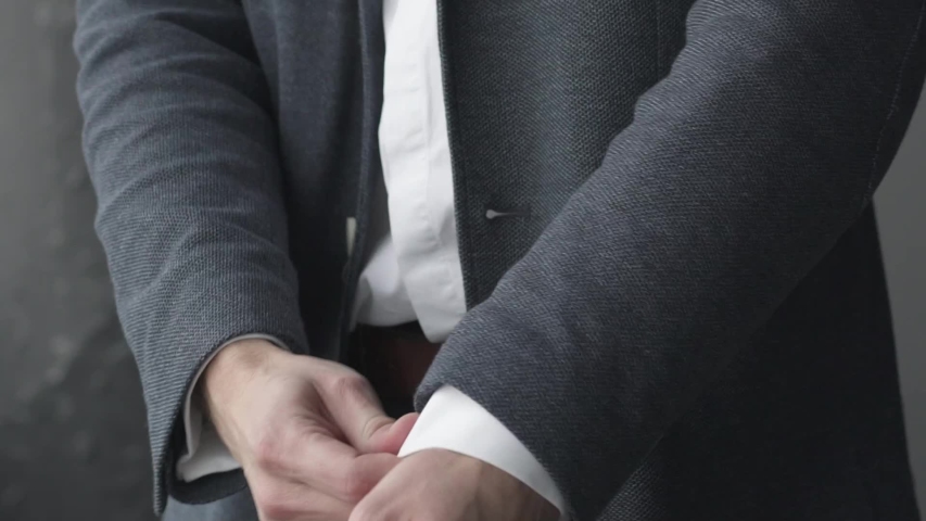 Business man close up preparing for meeting. Male fixes his cuffs on a jacket. White shirt. The groom getting ready for wedding. Well-dressed office manager checking his casual grey suit no tie 