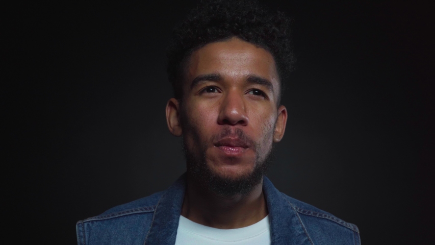 happy african american man blowing bubble gum on black