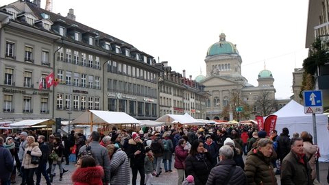 BERNE, SWITZERLAND - NOVEMBER 25, 2019: Visitors at the traditional Swiss Festival in Bern, called "Zibelemaerit" (market of onions), Fair of Onions, with swiss parliament in background
