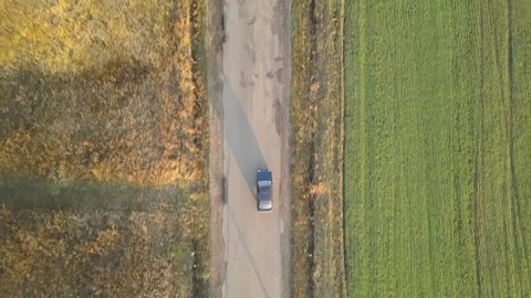 Top down aerial view of a car driving fast on bad road with potholes.