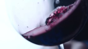 Waving red wine in a glass on defocused dark background . Beautiful stock footage for wine commercial . Close up video of wine mixing process inside goblet . Shot on ARRI ALEXA Camera in Slow Motion .