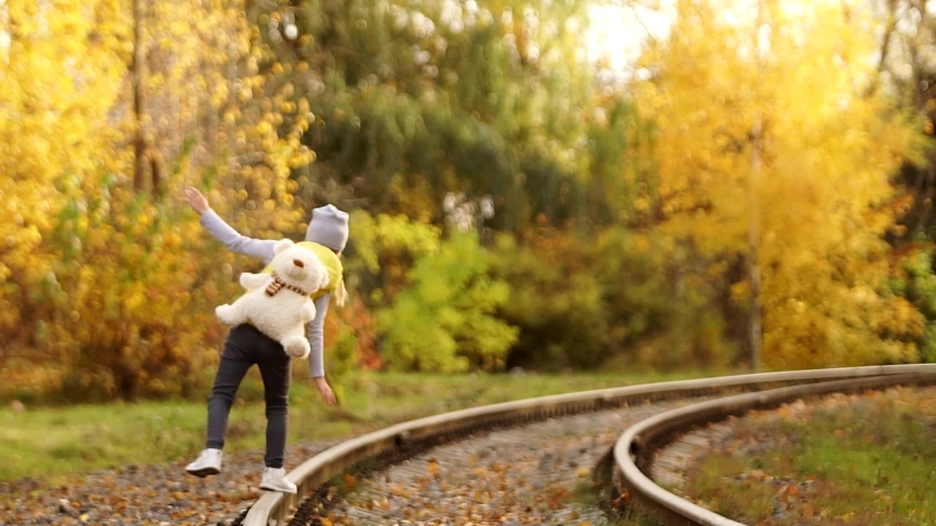 A little girl walks on the rails and admires nature.