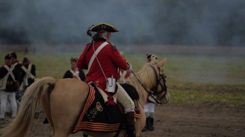 VIRGINIA - OCTOBER 16, 2018 - Reenactment, large-scale American Revolutionary War recreation -- in the middle of battle.  British Commander/General on horseback commands British Redcoat Soldiers.