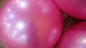 Closeup view of many big huge round pink gymnastics balls lying on floor of gym class. Real time full hd video footage.