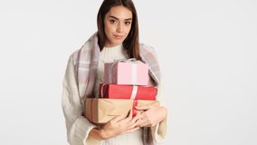 Beautiful girl with cozy plaid on shoulders shaking gift box and happily trying guess what is there over white background