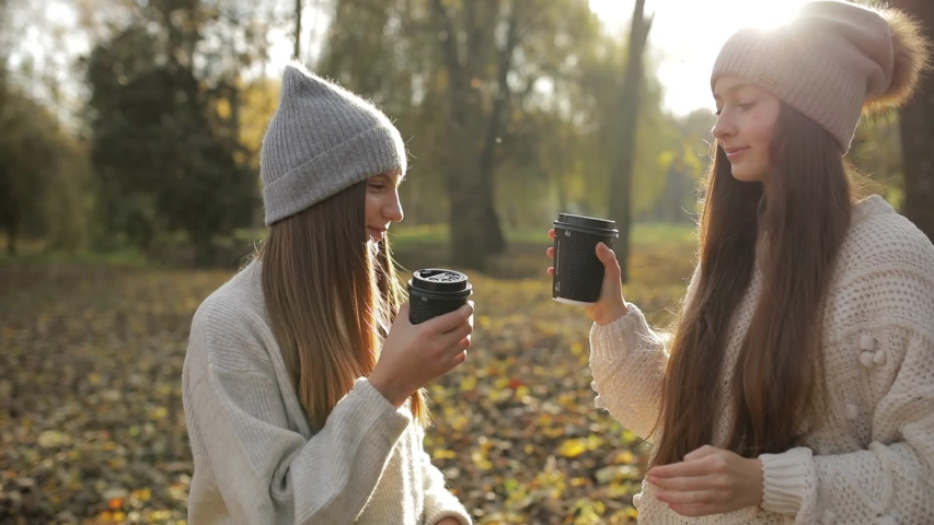 Young women drinking coffee in the park and enjoying autumn day | Shutterstock HD Video #1041663139