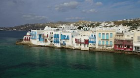 Aerial panoramic view video of world famous whitewashed little Venice picturesque settlement in main village of Mykonos island with beautiful deep blue sky and clouds, Cyclades, Greece