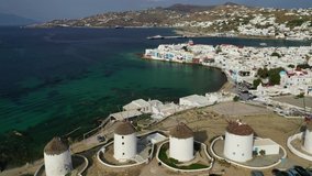 Aerial drone panoramic video of picturesque windmills and Little Venice in old port and main village of Mykonos island with beautiful colours at sunrise, Cyclades, Greece