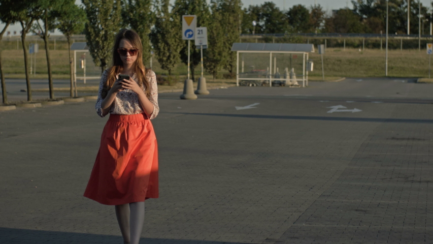 Beautiful caucasian girl walking down the street looking at her cell phone was almost hit by a car. Concept - smartphone addiction. Royalty-Free Stock Footage #1041669088