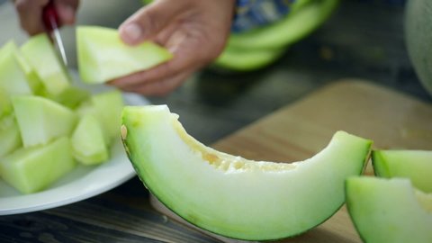 Chef sliced fresh sweet green melon and cut to small pieces put on white dish on wooden table.Slice to pieces of melon for easy eat and can make melon juice.Honeydew melon, also known as a honeymelon.