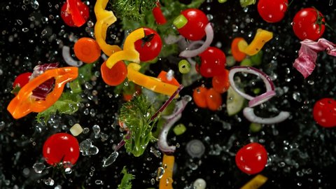 Super Slow Motion Shot of Flying Cuts of Colorful Vegetables and Water Drops on Black background at 1000fps.