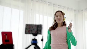 Asian women beautiful bloggers wear colourful clothes Such as green, pink Standing and dancing in headphones. Communicate sales to customers via live video. Online selling business via social media
