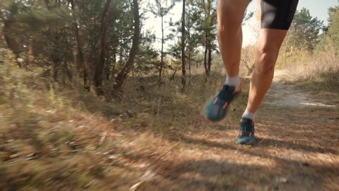 Running Man In Forest At Sunset.Runner Man Fit Athlete Legs Jogging On Trail Ready To Triathlon.Triathlete Running,Sprinting And Endurance Workout Training.Marathon Runner Jog On Trail.Sport Concept.
