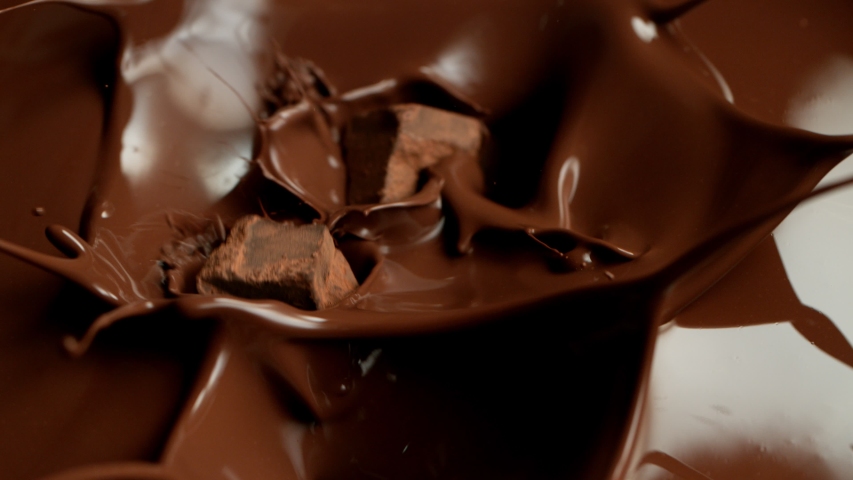 Super slow motion of flying raw chocolate pieces splashing into molten chocolate. Filmed on high speed cinema camera, 1000fps. Royalty-Free Stock Footage #1041680542
