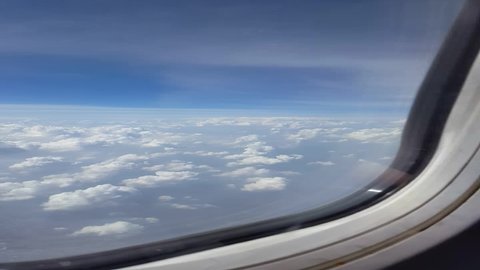 Airplane wing over blue sky and white cloud view looking through airplane window. Travel, vacation and journey concept.Soft focus,Select focus