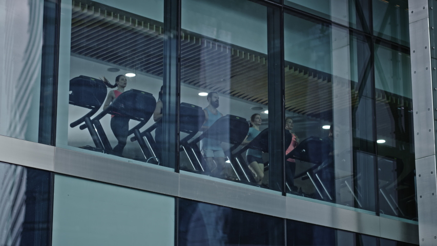 Athletic People Running on Treadmills, Doing Fitness Exercise. Fit and Muscular Athletes Actively Training in the Modern Gym. Sports People Workout. Low Angle Slow Motion. Camera Outside Building Royalty-Free Stock Footage #1041686413